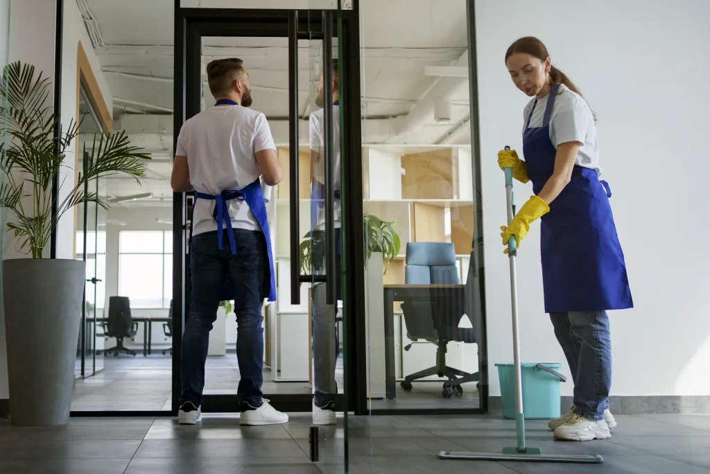 Addetti di un'impresa di pulizie in divisa al lavoro negli uffici di un'azienda
